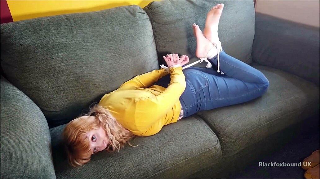 Barefoot white girl is hogtied on a sofa while ball gagged in her clothing 色情照片 #425132906