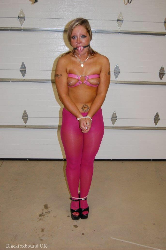 In pink pantyhose and heels, the dirty blonde performs a ball gag.