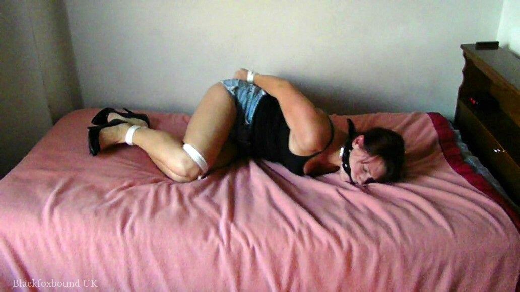 A Brunette woman was left on a bed with her legs tied up and gagged.