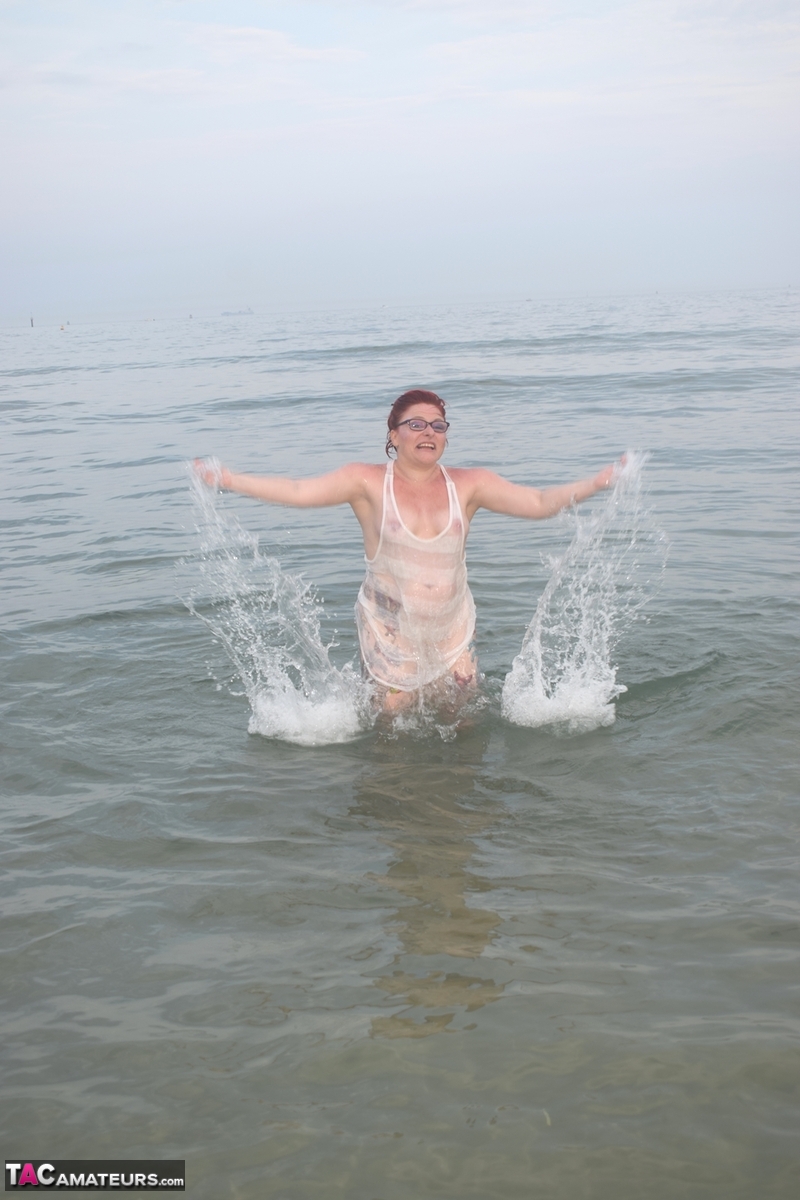 Before exposing herself, the tattooed redhead ventures out into the sea.