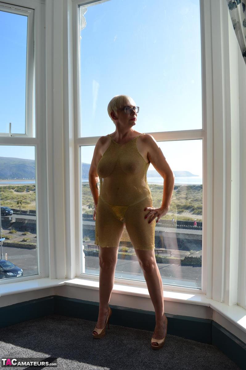 Big titted older woman Barby Slut showcases her bald twat in front of a window porn photo #424802960