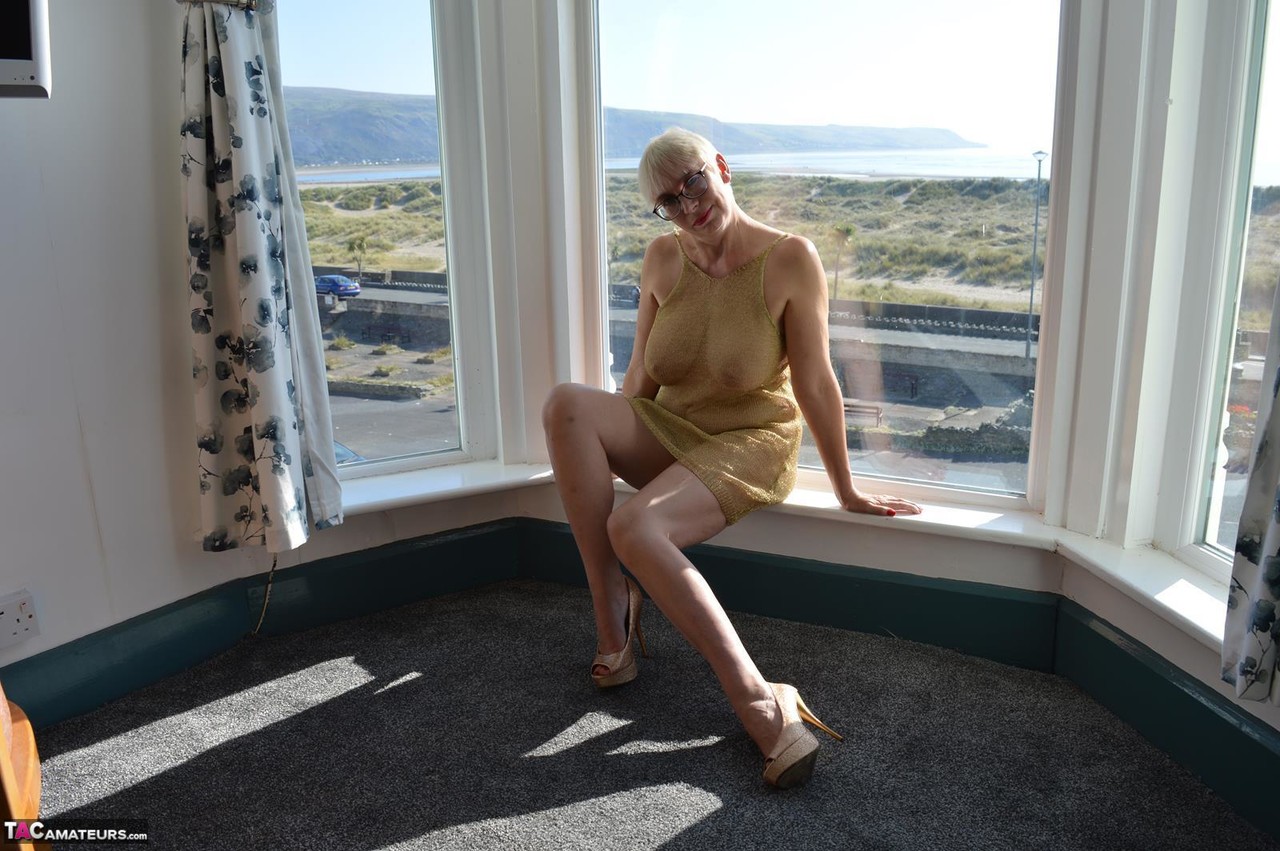 Big titted older woman Barby Slut showcases her bald twat in front of a window porn photo #424802974