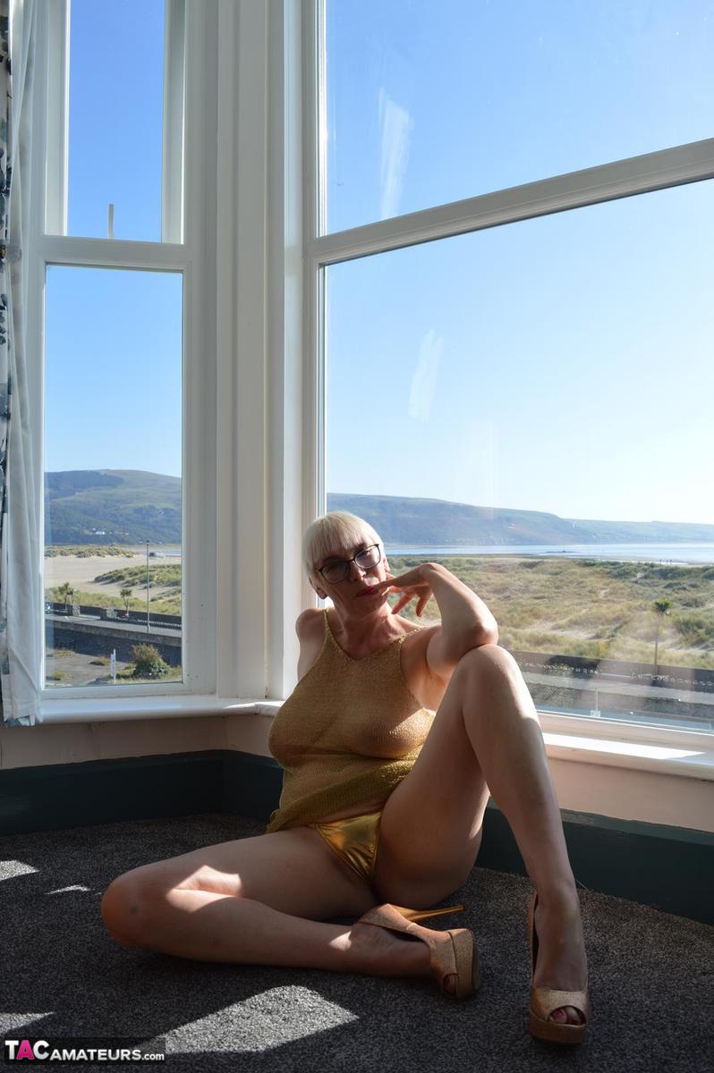 Big titted older woman Barby Slut showcases her bald twat in front of a window porn photo #424803000