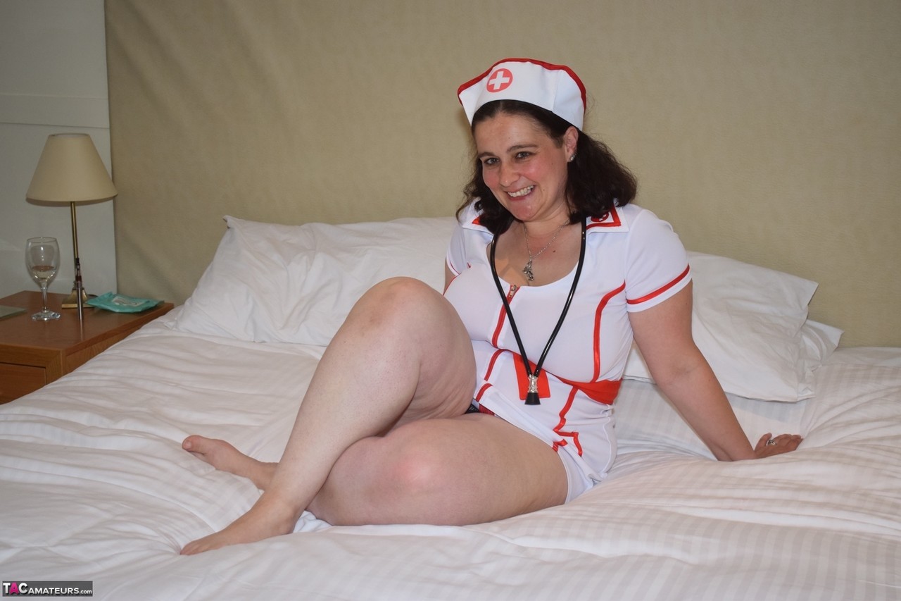 Overweight nurse removes her uniform to model nude in black panties on a bed zdjęcie porno #427172697