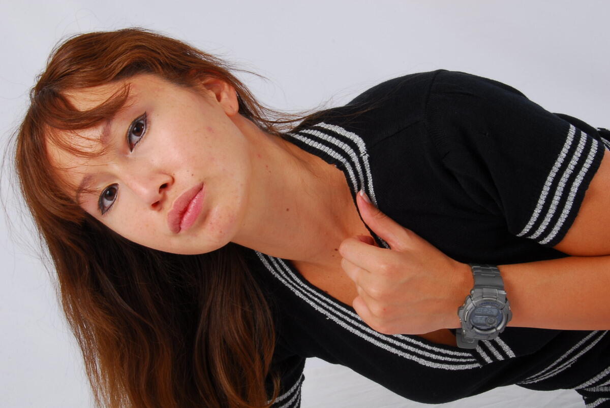 A grey G-Shock watch is worn by the Asian redhead Evita, who is fully clothed in a suit.