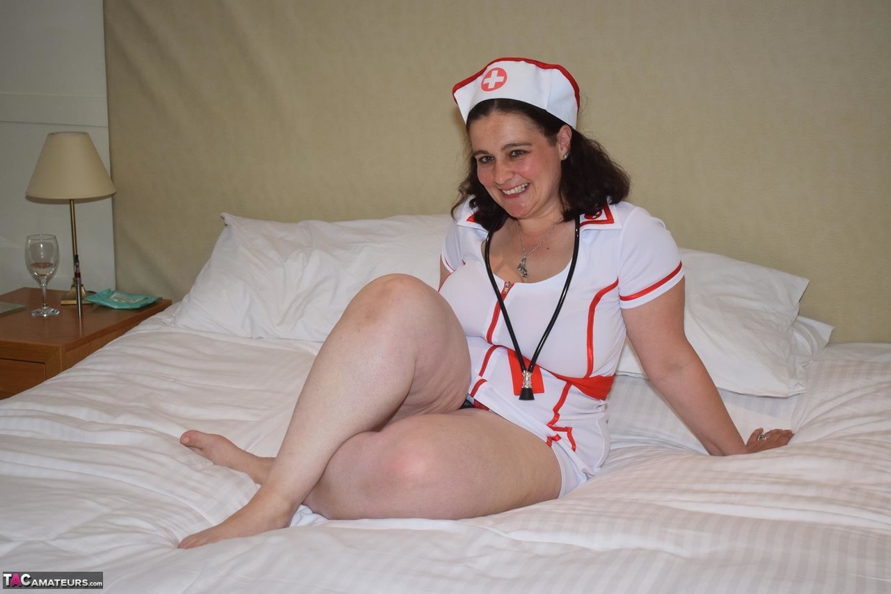 Overweight Brunette Sets Her Big Boobs Free Of Naughty Nurse Attire On A Bed