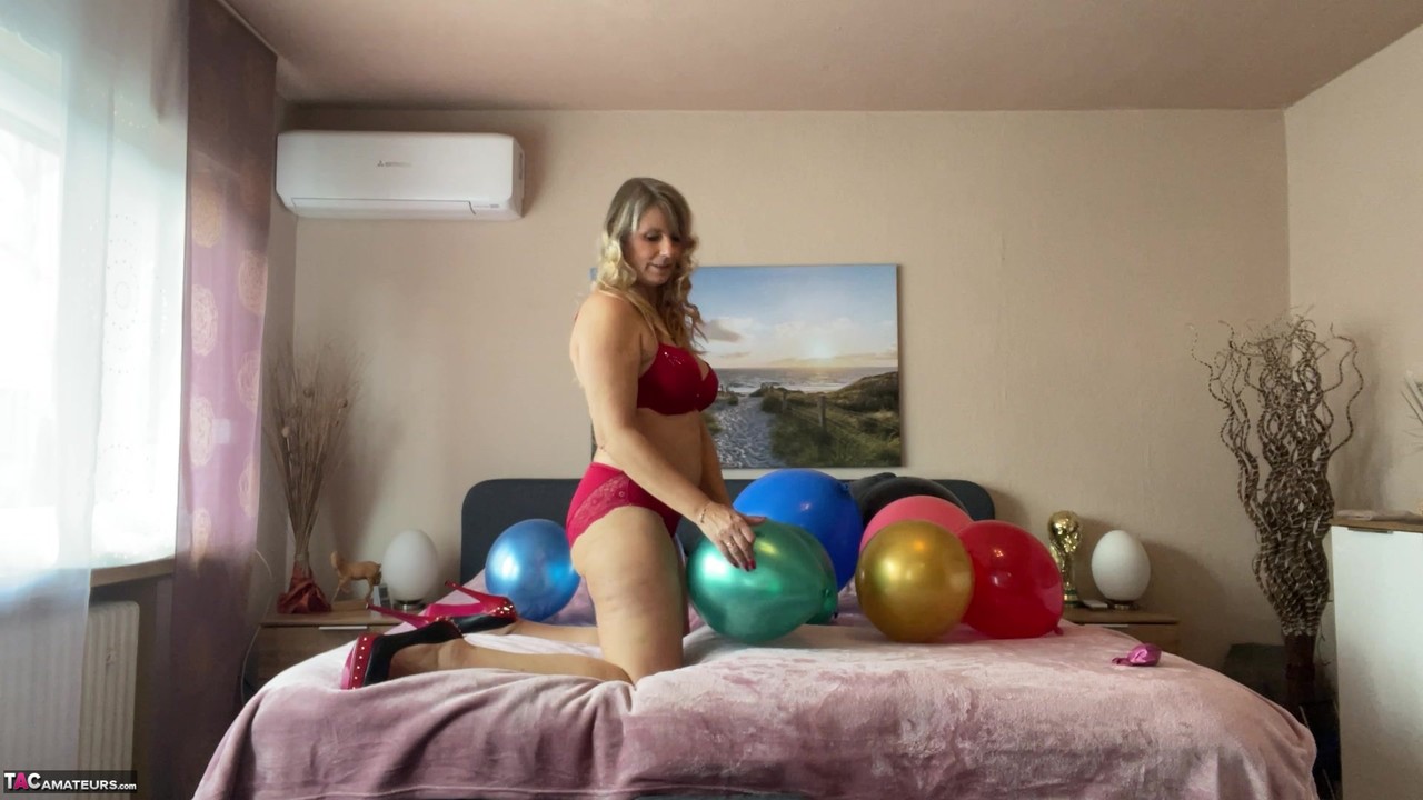 Middle-aged blonde Sweet Susi plays with balloons while getting naked on a bed porn photo #425401764