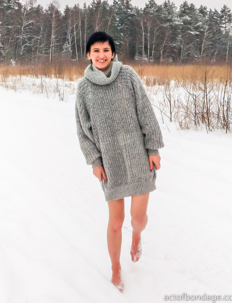 Claudia, a naked girl with short black hair, kneels on snow-covered ground while being gagged.