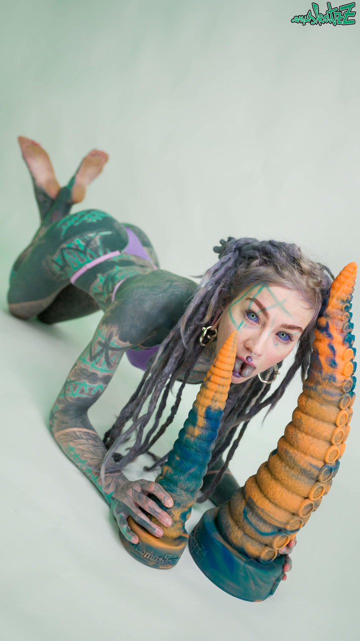 Heavily tattooed girl Anuskatzz holds a couple of taintacle toys in the nude porn photo #422703324