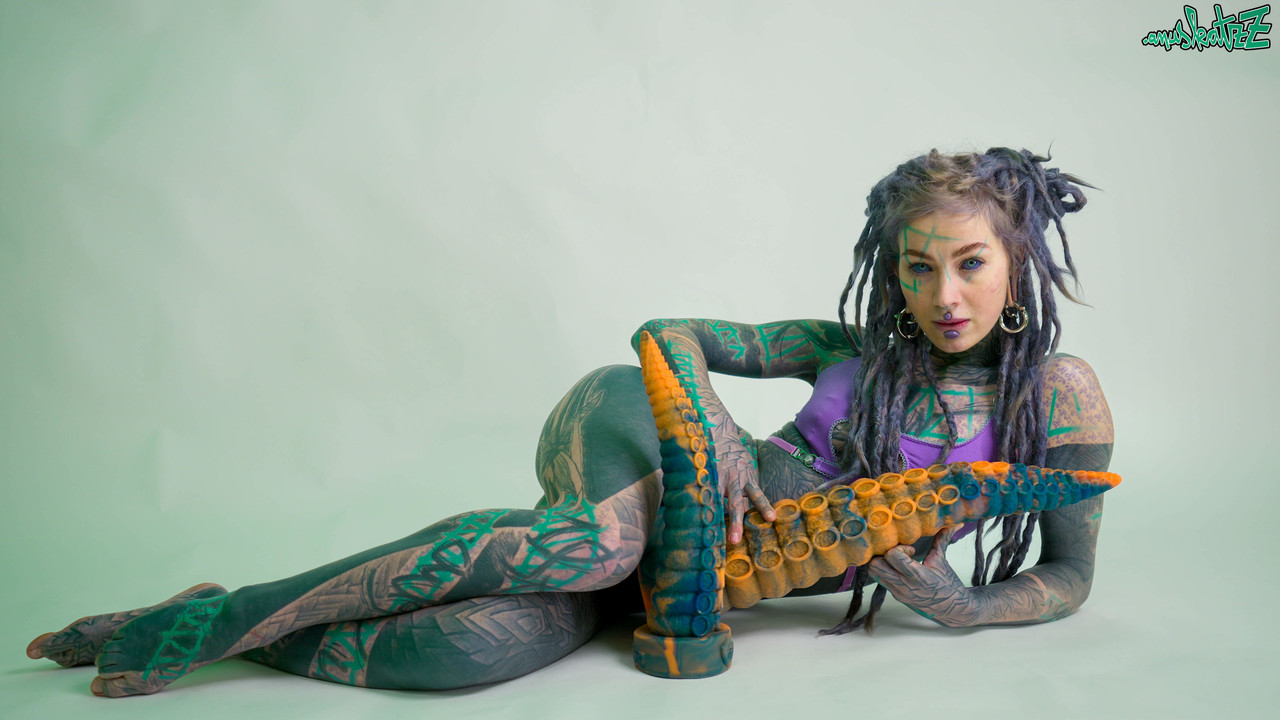 Heavily tattooed girl Anuskatzz holds a couple of taintacle toys in the nude photo porno #422703370