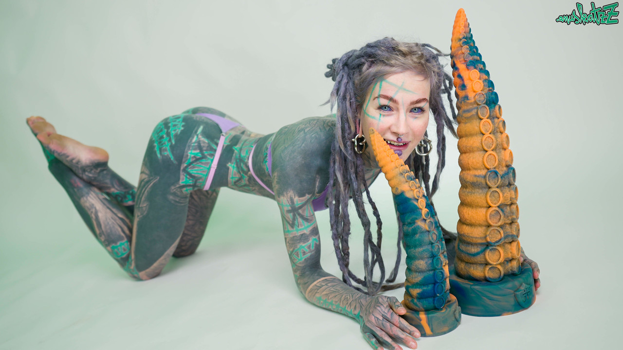 Heavily tattooed girl Anuskatzz holds a couple of taintacle toys in the nude porno foto #422703621