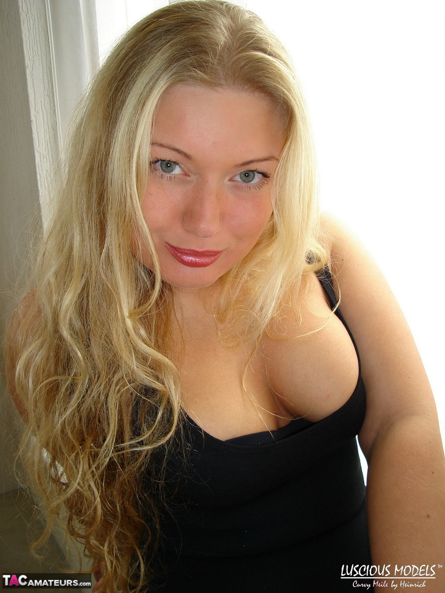 Natural blonde Luscious Models exposes her breasts beneath a black swimsuit.