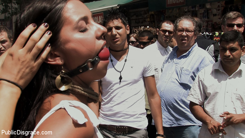 Prior to being publicly sexted, the brunette girl is guided through the city streets in the nude.