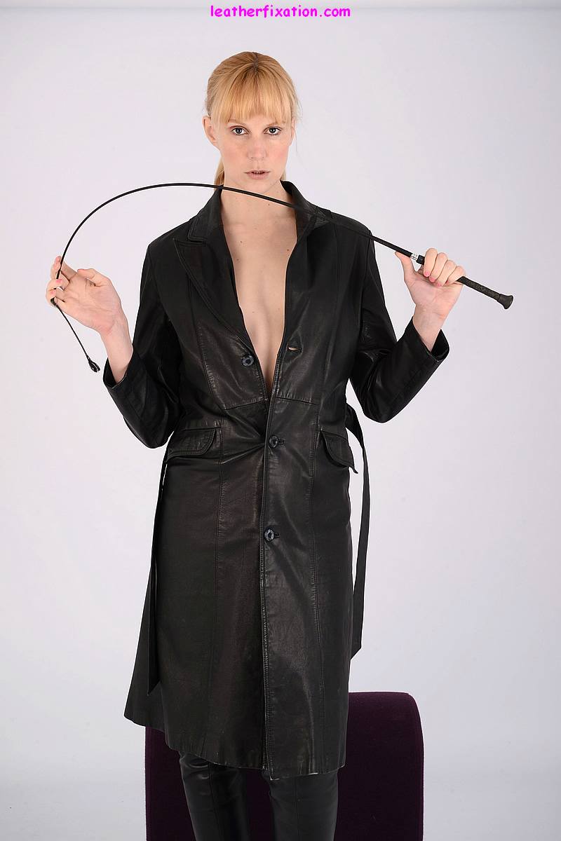 Pale woman flexes a whip before undoing a leather overcoat in matching boots porn photo #428165443