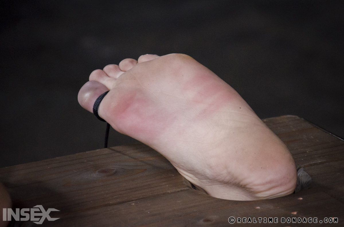 Violet Monroe's blonde locks flaunt elegant red toes while being held in bondage.