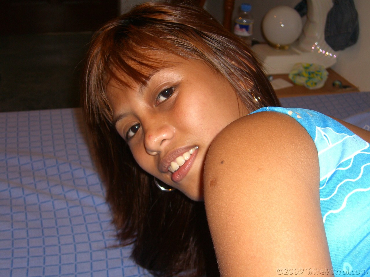 A Filipina amateur removes her clothes for the first time to bare it on a bed during a nude shoot.