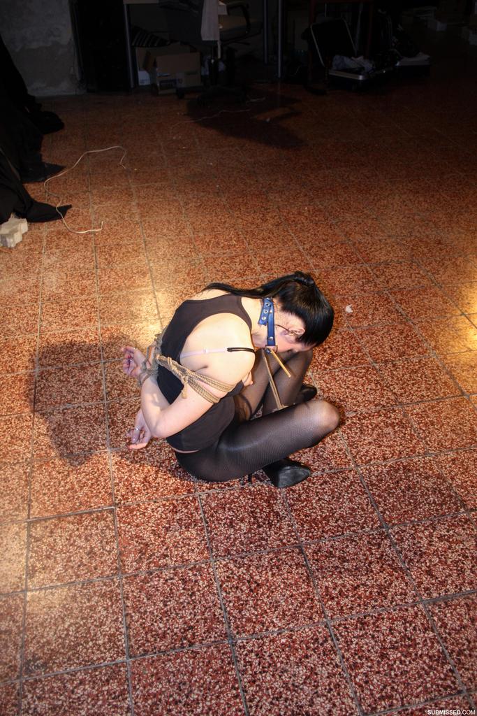 A brunette woman in pantyhose is restrained with rope and left to struggle.