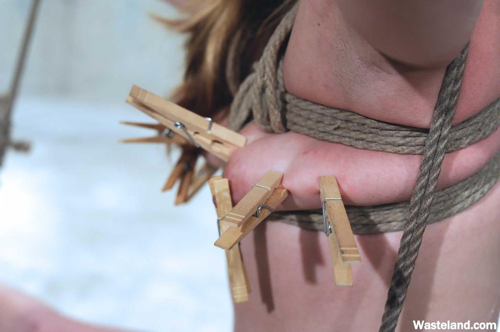 Hot wax and clothespins are used to torture a female who is suspended in pain.