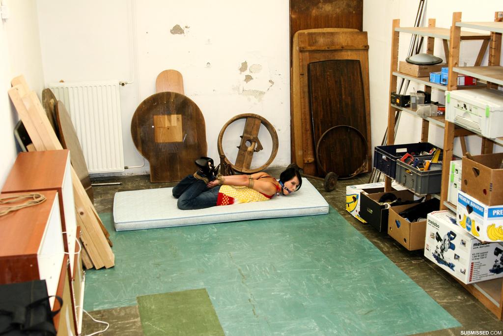 A scantily-clad woman with dark hair struggles to grip her rope bounds.