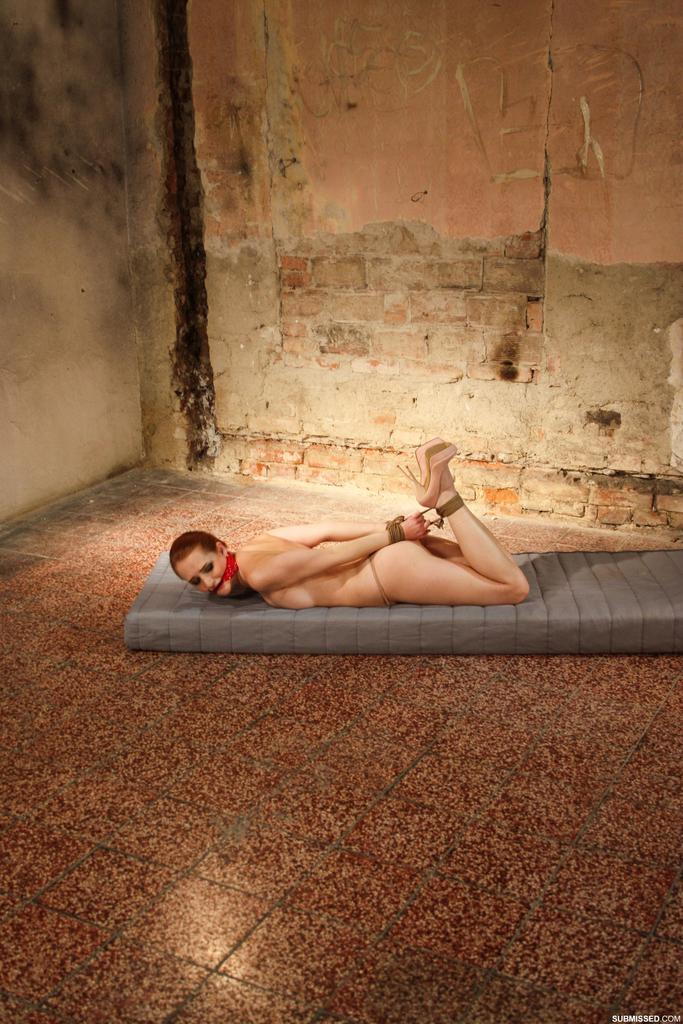 A mattress is the location where a redhead female is gagged, hogtied, and left face down.