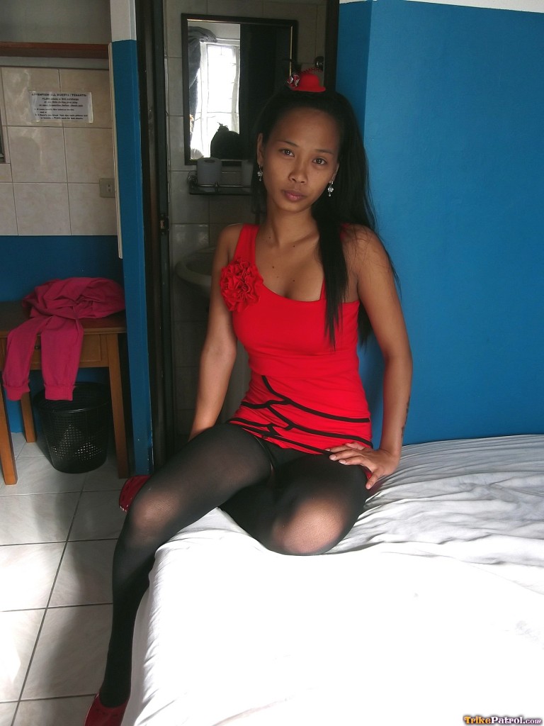While Trisha Mae, a slim Asian female, displays her pussy on a bed, she also turns over her red dress.