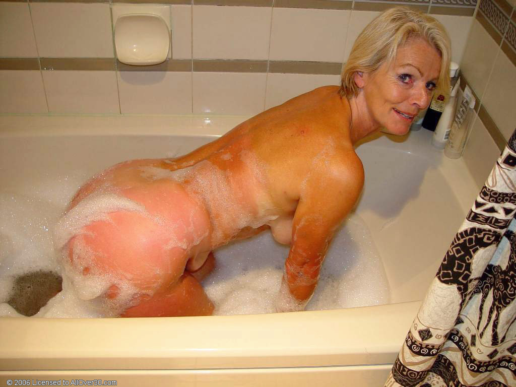 Justine, a gorgeous woman of adulthood, enjoys lounging in the bathtub with her big breasts and hairy pussy.