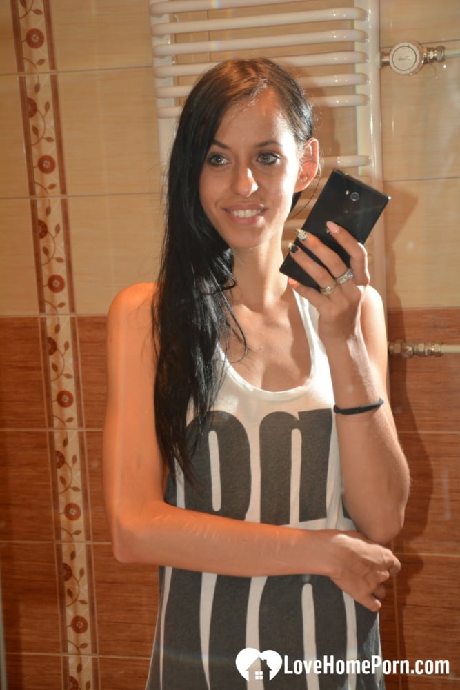 In the mirror, a beautiful amateur brunette exposes her medium breasts while stripping.