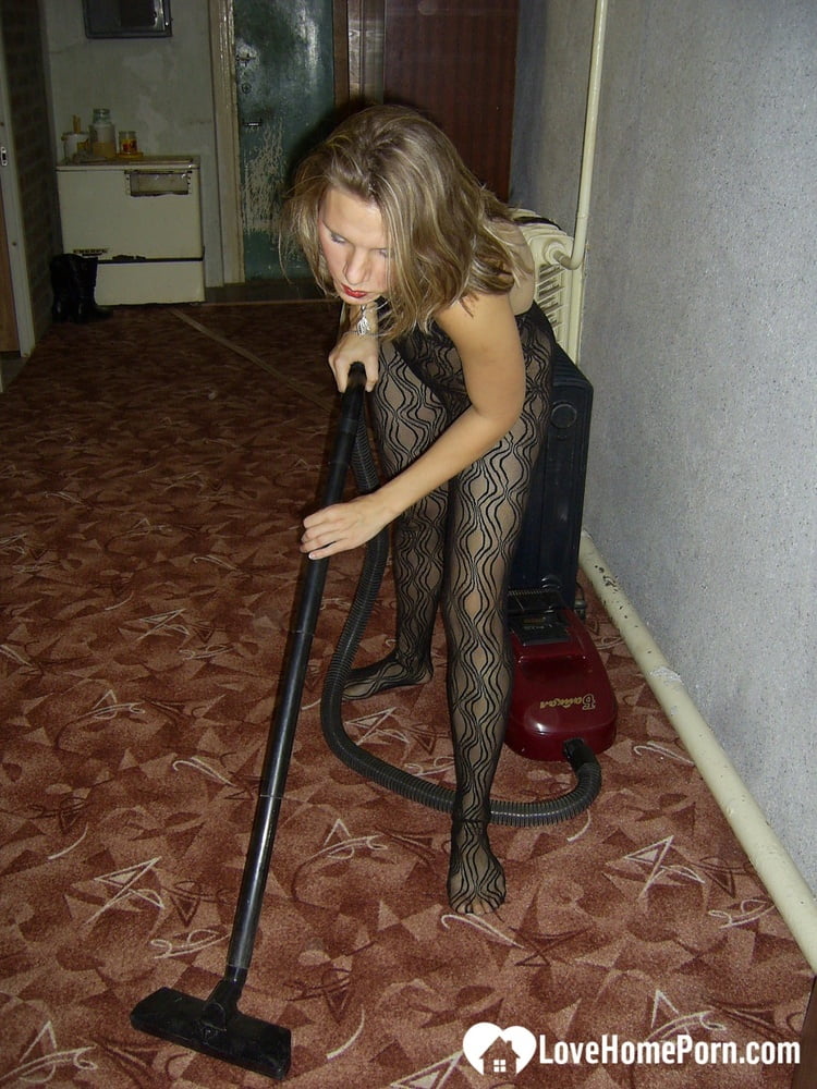 A fat lady who wears red lipstick is seen in her bodystock vacuuming.