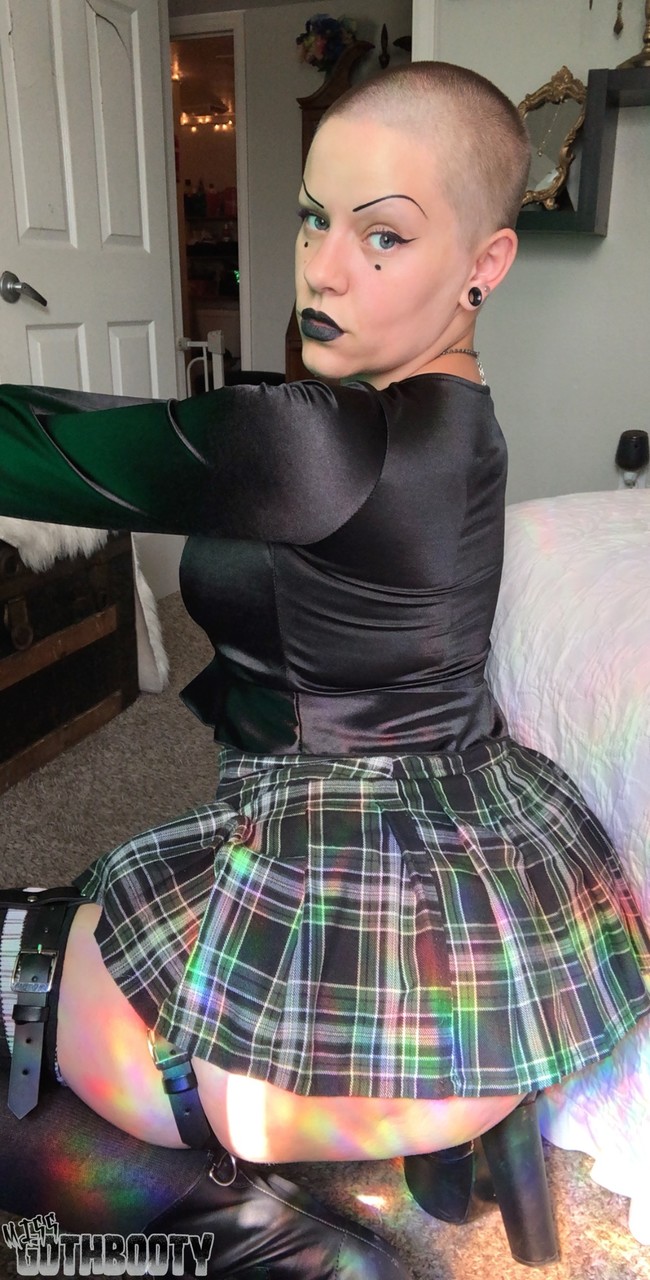 In a Bald MILF top, Miss Goth Booty exposes her large buttocks while wearing a plaid skirt.