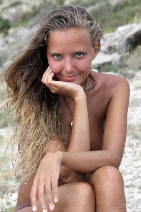 La chica sola Mango A modelando desnuda en una playa rocosa después de