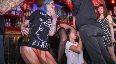 A submissive girl is subjected to public spit roasting and then sexual intercourse with her penis before she performs oral sex in a bar.