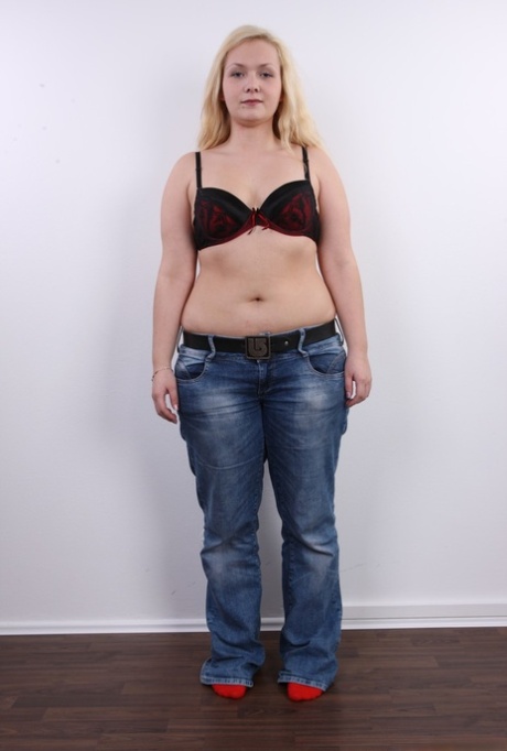 Lucie, a fat girl with blonde hair, removes her clothing and stands naked on her buttocks.