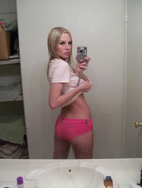 Blonde amateur: Aimee takes mirror selfies while hiding her boobs, looking at the camera proudly.