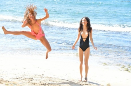 2 Lesbians Frolic In Swimsuits At The Beach Before Strolling In The Nude