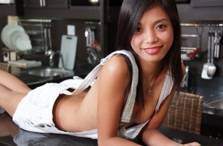The kitchen is where the attractive Asian girl disrobes and spread out, showing off her pussy.