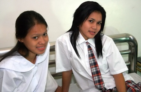 A small cock is seen kissing Asian schoolgirls before a threesome on a bed.