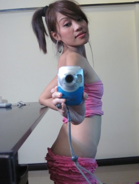 Cute teen Asian takes self shots in a mirror while getting naked