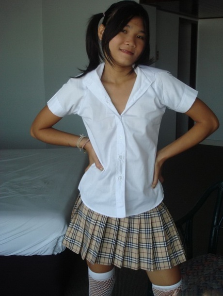 An Asian girl removes her schoolgirl attire to reveal her bare haird figure.