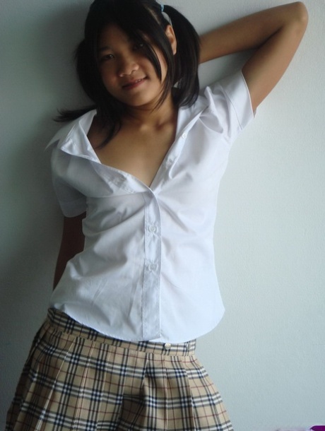 A young Asian girl removes her schoolgirl attire to reveal her bare haired body.