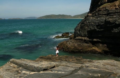 Asian teen makes her nude modelling debut as the surf pounds the coast below