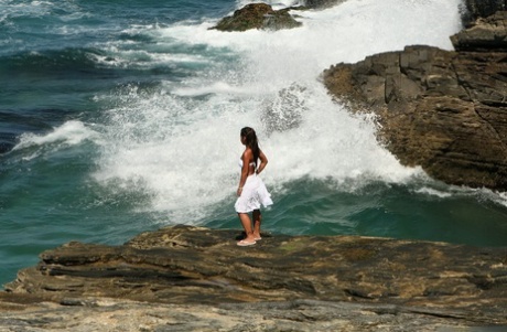 Asian teen makes her nude modelling debut as the surf pounds the coast below