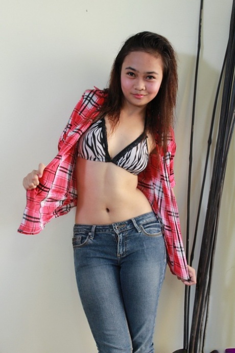 Asian teenager in blue jeans undresses to pose in the nude for the first time