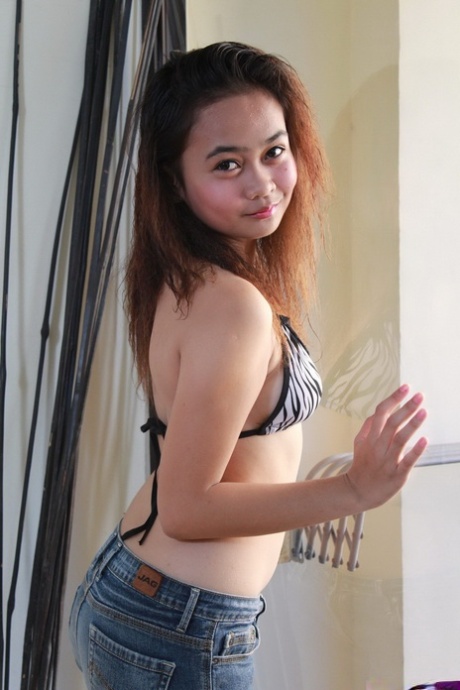 Asian teenager in blue jeans undresses to pose in the nude for the first time