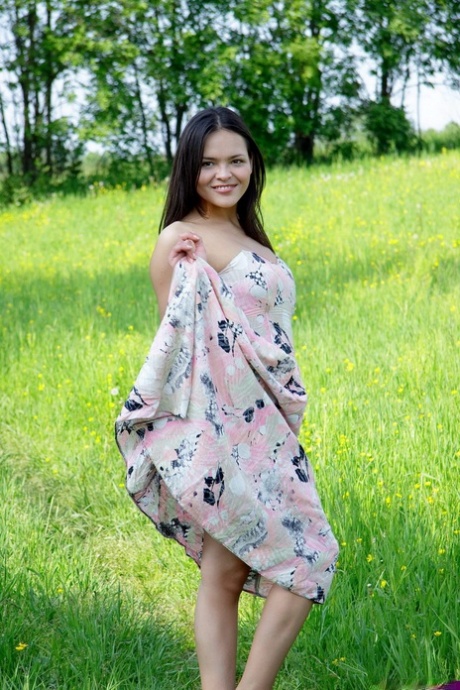 Nice Asian teen frees her breasts and pussy from her dress in a grassy meadow