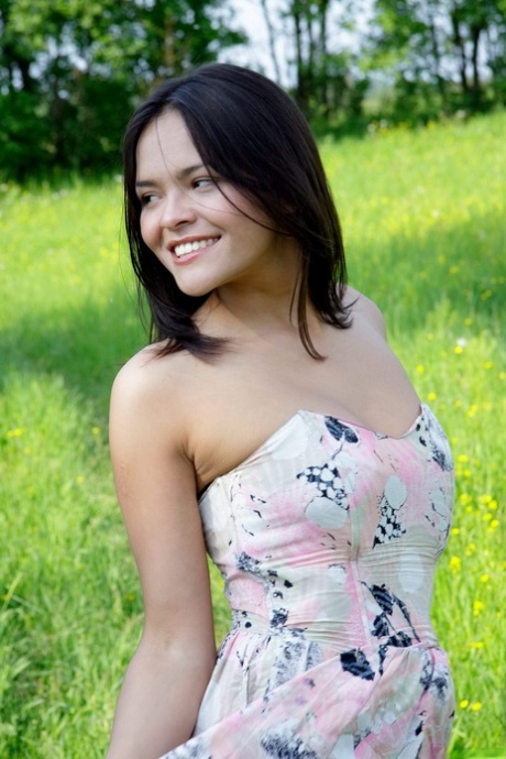 A lovely Asian girl releases her breasts and pussy from the side of she is wearing a dress in a grassy meadow.