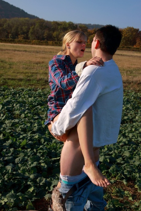 In a field with no visible surfaces, a blonde girl and her boyfriend engage in sexual activity while being unnoticed.