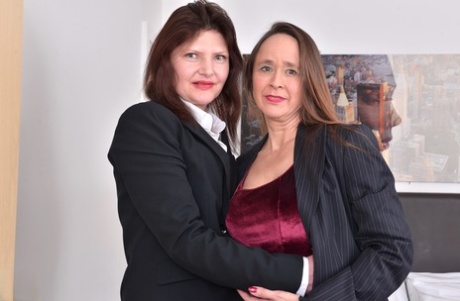 Mature British women dress in business attire before having lesbian sex.