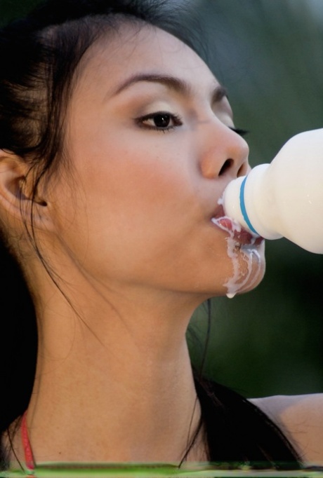 Сексуальная азиатская девушка получает молоко по всему ее красивому лицу и красивым грудям