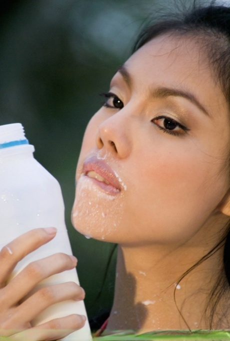 A beautiful, attractive Asian woman with sexy facial skin and breasts is covered in milk.