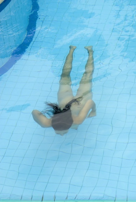 A little Asian girl in full form, wearing tight-fitting trousers and swimmingly while bathing naked in a pool.